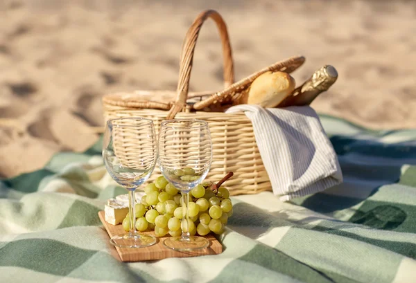Cesta de piquenique com copos de vinho e comida na praia — Fotografia de Stock