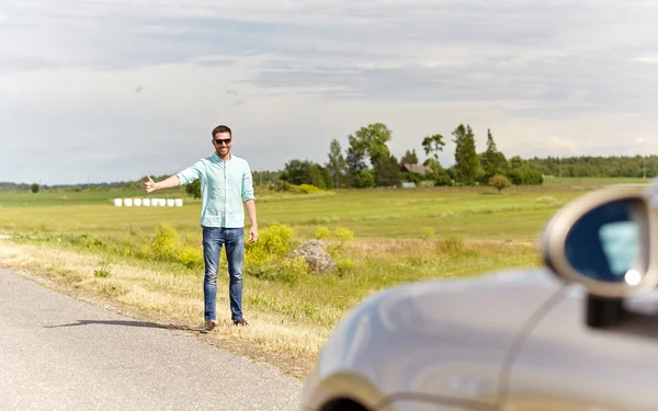 Man hitchhiking and stopping car at countryside — Stock Photo, Image