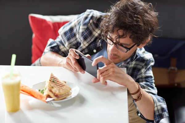 Homem com smartphone fotografar alimentos no café — Fotografia de Stock