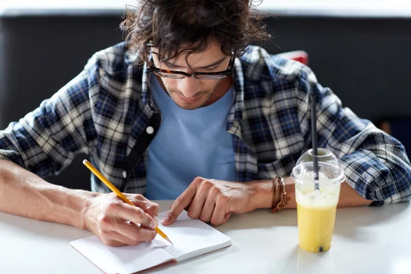 Homme avec cahier et jus écrit au café — Photo