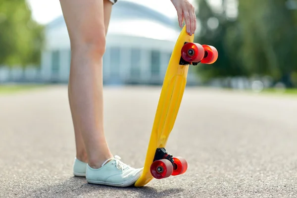 Close-up van vrouwelijke voeten met kort skateboard — Stockfoto