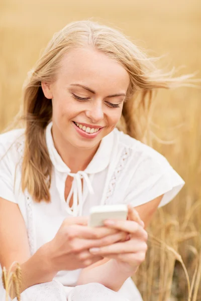 Jovem feliz com smartphone no campo de cereais — Fotografia de Stock