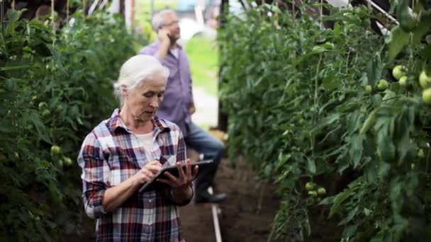 Стара жінка з планшетним ПК в теплиці на фермі — стокове відео