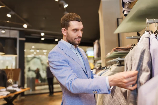 Šťastný mladý muž výběru oblečení v obchod s oblečením — Stock fotografie