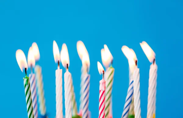 Velas de cumpleaños ardiendo sobre fondo azul — Foto de Stock