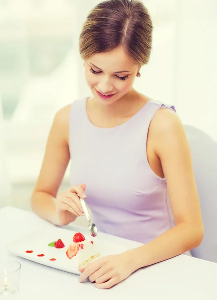 Улыбающаяся молодая женщина ест десерт в ресторане — стоковое фото