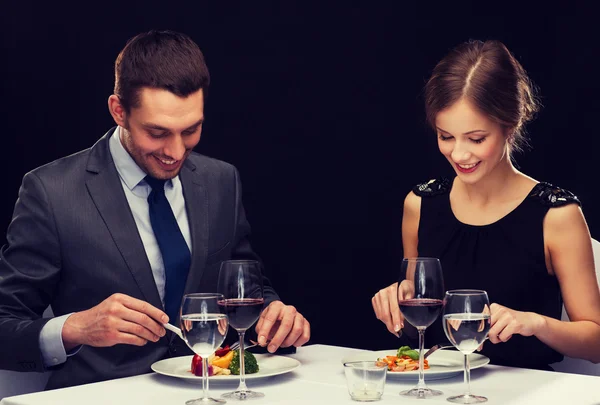 Sonriente pareja comiendo plato principal en restaurante — Foto de Stock