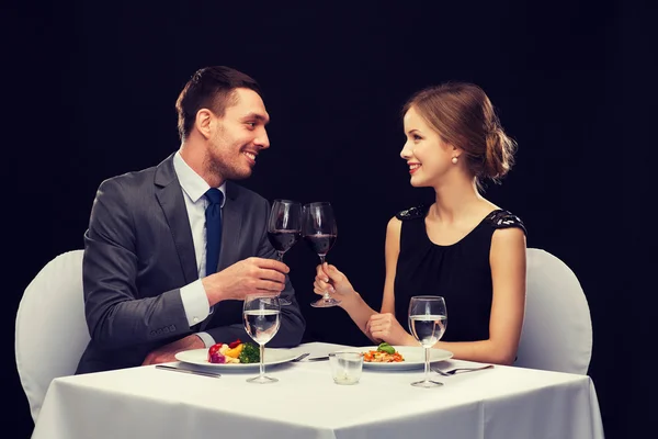 Sonriente pareja comiendo plato principal en restaurante —  Fotos de Stock