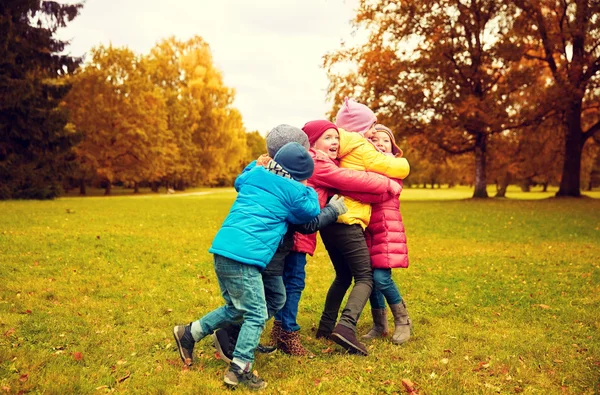 Ομάδα ευτυχισμένα παιδιά αγκάλιασμα στο πάρκο φθινόπωρο — Φωτογραφία Αρχείου