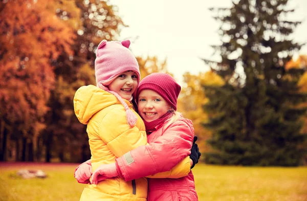 Duas meninas felizes abraçando no parque de outono — Fotografia de Stock