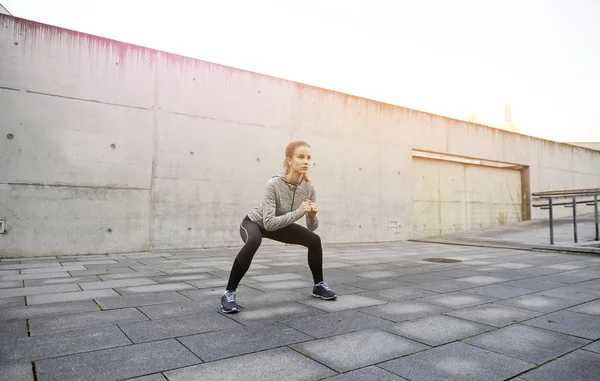 Ευτυχισμένη γυναίκα κάνει τις στάσεις οκλαδόν και άσκηση σε εξωτερικούς χώρους — Φωτογραφία Αρχείου