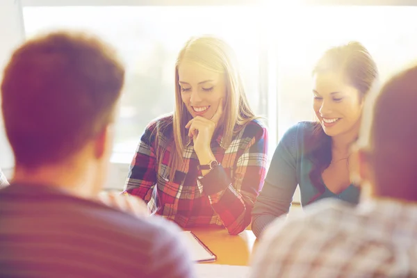 Group of smiling students sitting at table — Stock Photo, Image