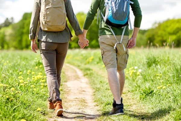 Close up of couple with backpacks walking on road — Stock Photo, Image