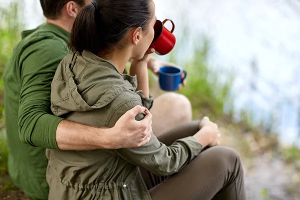 Gelukkige paar met kopjes drinken in de natuur — Stockfoto