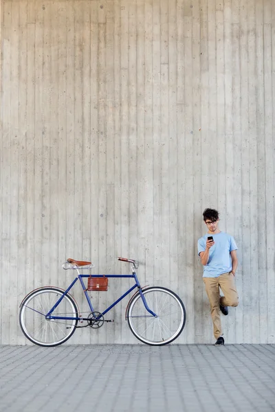 Человек со смартфоном и велосипедом с фиксированной передачей на улице — стоковое фото