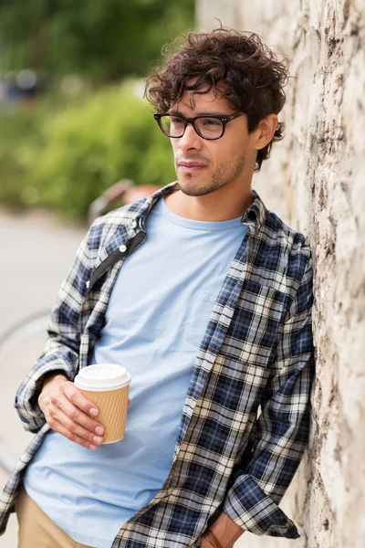 Man in eyeglasses drinking coffee over street wall — Stock Photo, Image