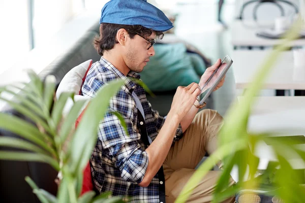 Hombre con la tableta PC sentado en la mesa de la cafetería — Foto de Stock