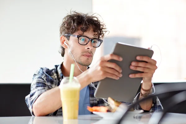 Homem com tablet pc e fones de ouvido sentado no café — Fotografia de Stock