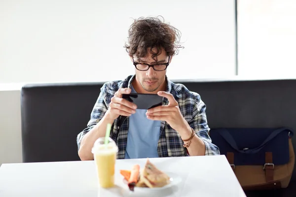 Mann mit Smartphone fotografiert Essen im Café — Stockfoto