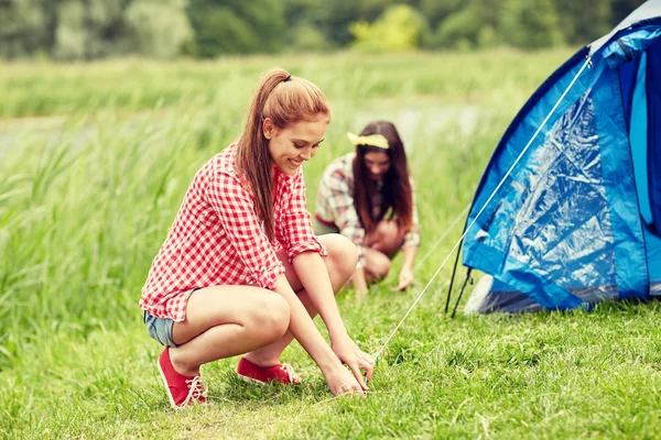 Smiling friends setting up tent outdoors — Stock Photo, Image