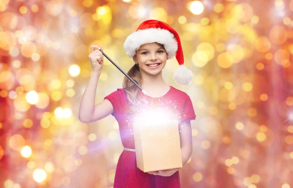 Niña en sombrero de santa con caja de regalo y varita mágica — Foto de Stock