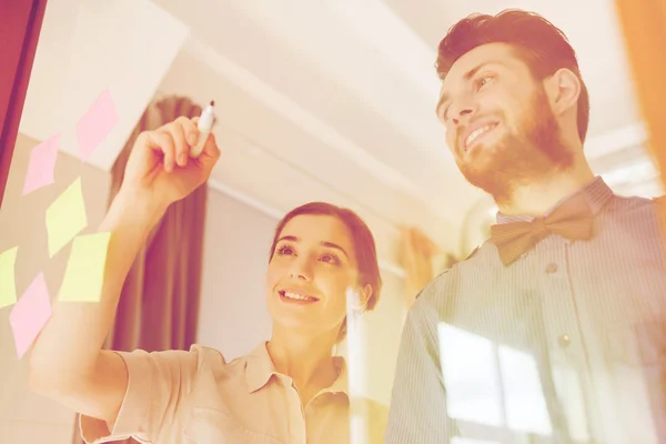 Feliz equipo creativo escribiendo en vidrio de oficina en blanco — Foto de Stock