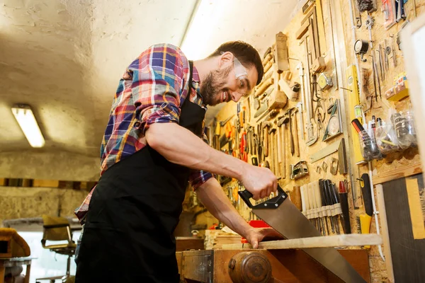 Carpenter working with saw and wood at workshop — Stock Photo, Image