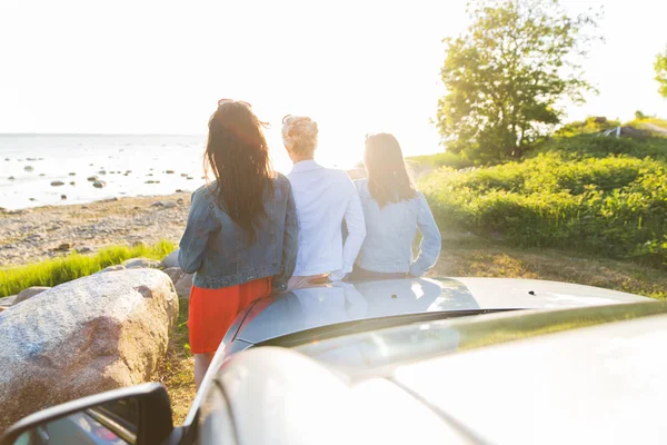 Щасливі дівчата-підлітки або жінки біля машини на морі — стокове фото