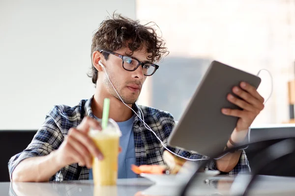 Hombre con tablet PC y auriculares sentados en la cafetería —  Fotos de Stock