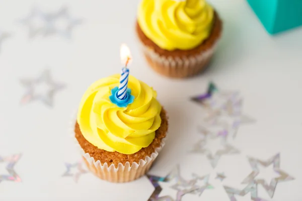 Кексы на день рождения с горящими свечами — стоковое фото