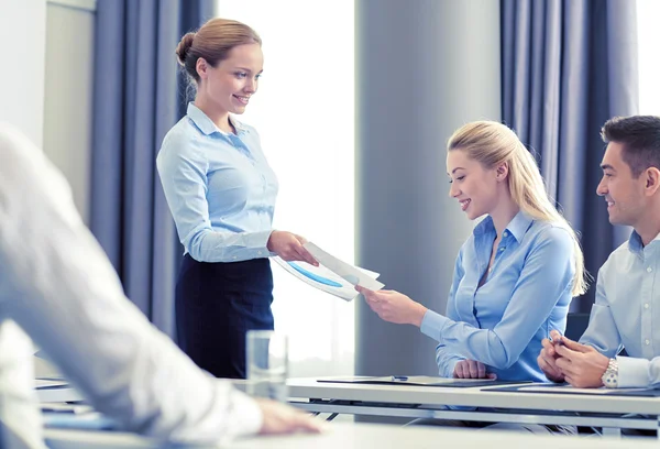 Mujer dando papeles al grupo de empresarios — Foto de Stock