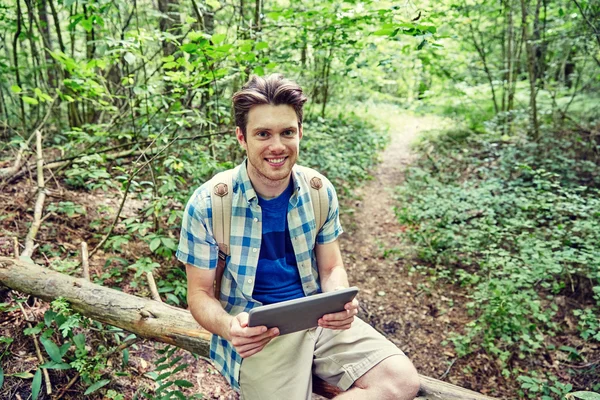 Glücklicher Mann mit Rucksack und Tablet-PC im Wald — Stockfoto