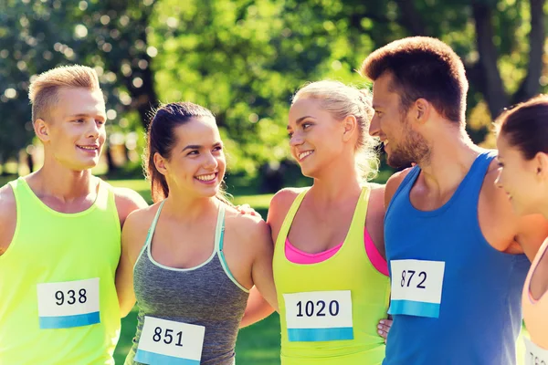 Happy friends or couple with racing badge numbers — Stock Photo, Image