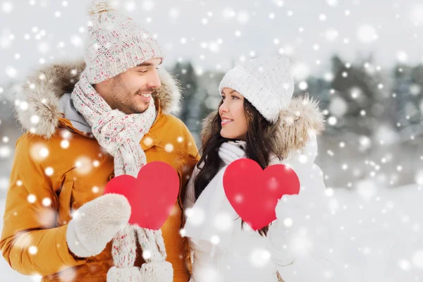 Feliz pareja con corazones rojos sobre el paisaje de invierno —  Fotos de Stock