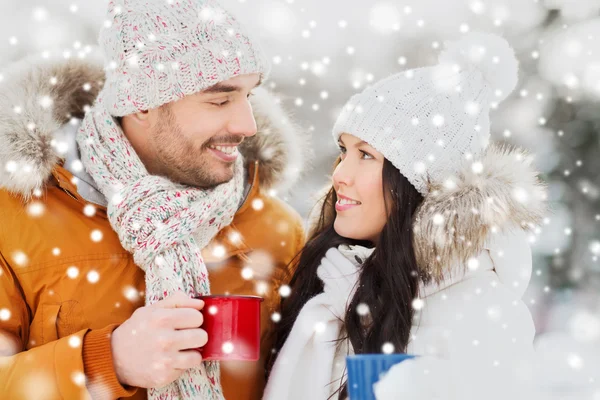 Casal feliz com xícaras de chá sobre paisagem de inverno — Fotografia de Stock