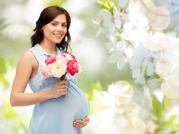 Glückliche schwangere Frau mit Blumen, die Bauch berühren — Stockfoto