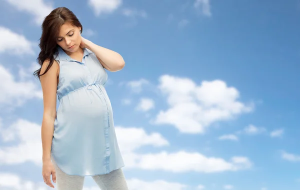 Pregnant woman with neckache over blue sky — Stock Photo, Image