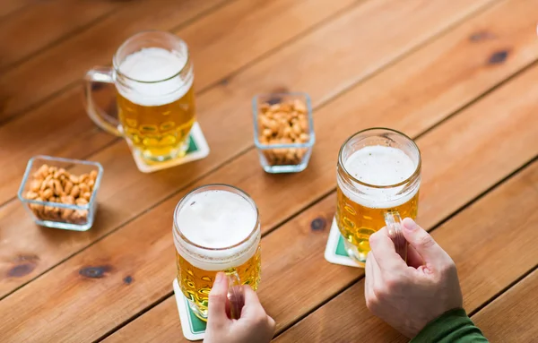 Close up de mãos com canecas de cerveja no bar ou pub — Fotografia de Stock