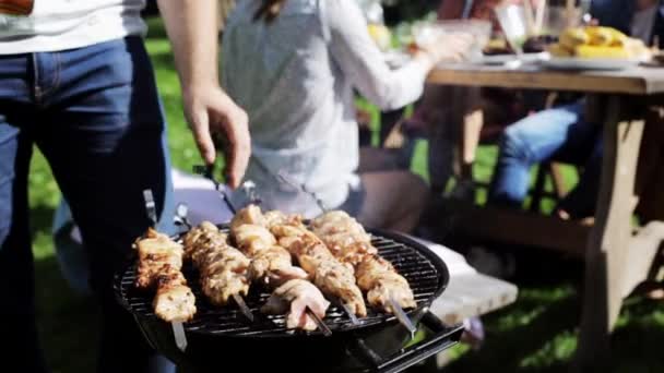Man cooking meat on barbecue grill at summer party — Stock Video