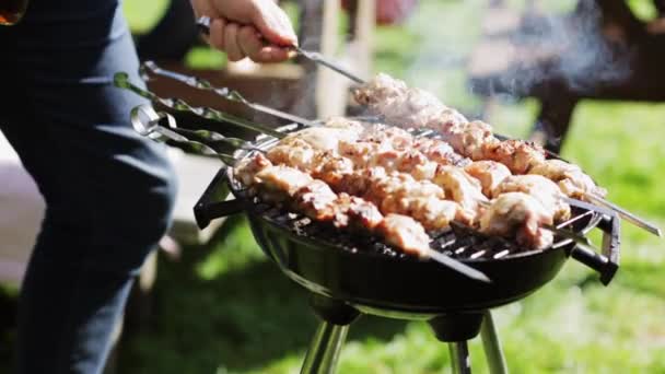 Man koken van vlees op barbecue grill op zomer feest — Stockvideo
