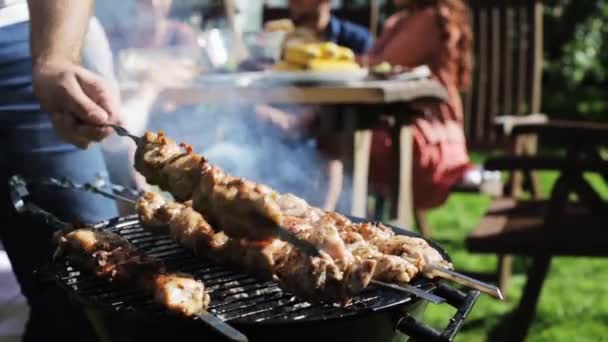 Счастливые друзья на вечеринке барбекю в летнем саду — стоковое видео