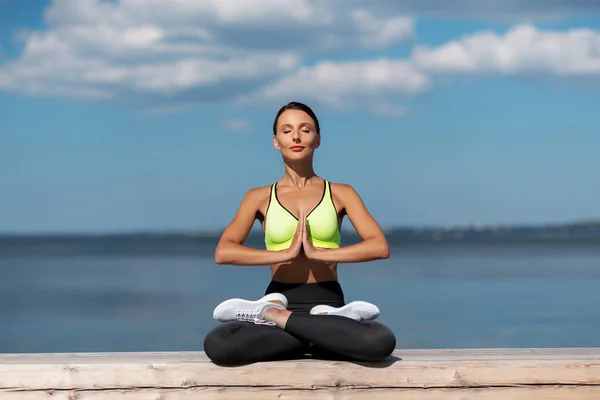 Ung kvinna mediterar i lotus poserar vid havet — Stockfoto