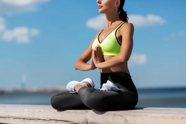 Молодая женщина медитирует в позе лотоса на берегу моря — стоковое фото