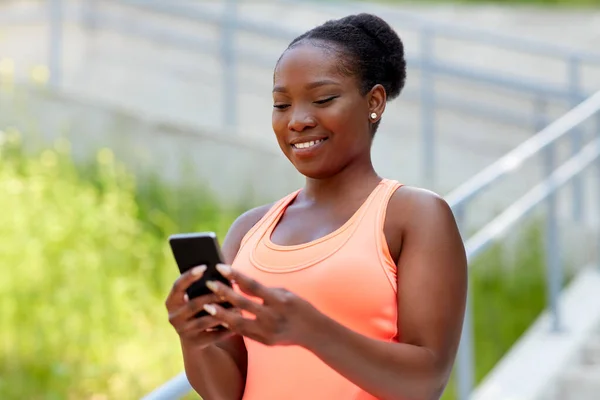 Femme africaine sportive utilisant un smartphone en ville — Photo
