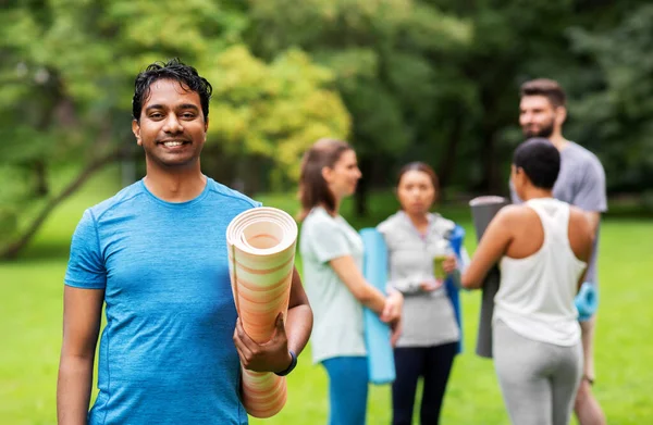 Glimlachende man met yoga mat over groep mensen — Stockfoto