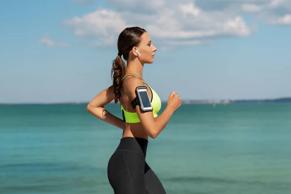 Mujer con auriculares y smartphone funcionando — Foto de Stock