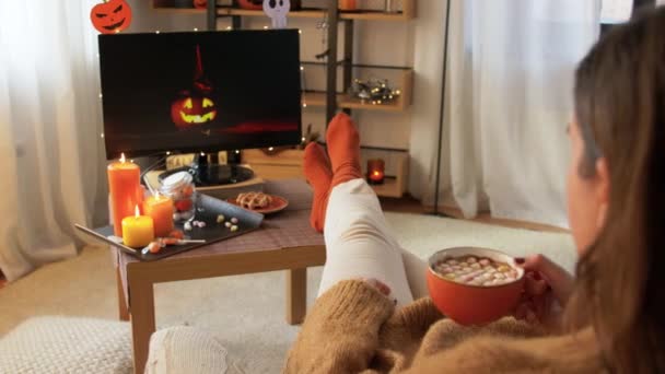 Vrouw kijkt tv en drinkt cacao op halloween — Stockvideo