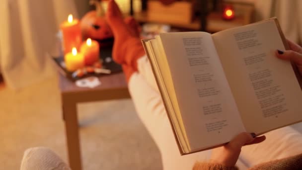 Mladá žena čtení knihy doma na Halloween — Stock video