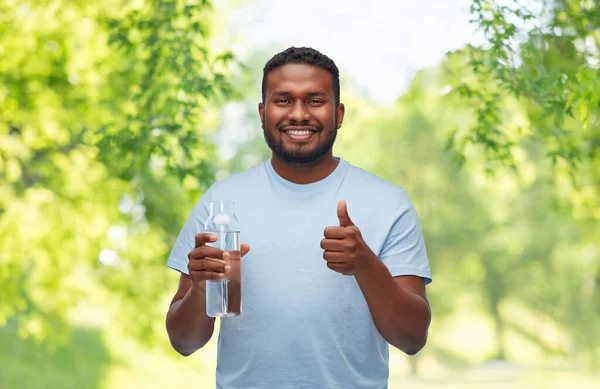Hombre africano feliz con agua en botella de vidrio —  Fotos de Stock