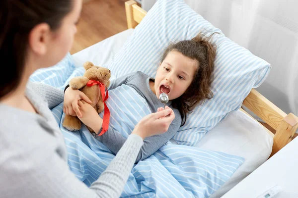 Mother giving cough syrup to sick daughter — Stock Photo, Image